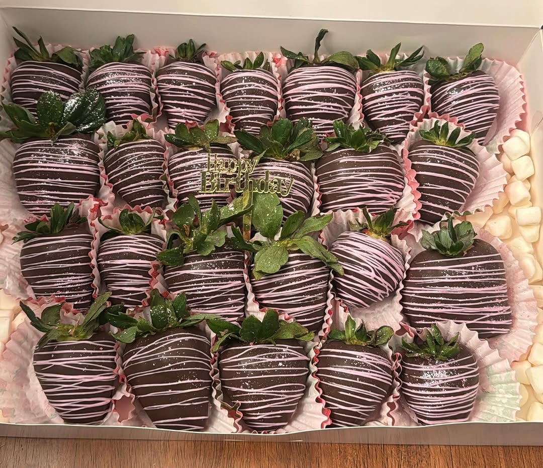 Large birthday order of over twenty dark chocolate strawberries with pink and white drizzle, edible glitter, and a gold Happy Birthday topper.